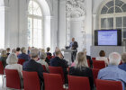 Blick in Saal, Innenminister Joachim Herrmann hinter Rednerpult, daneben Präsentation