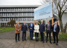 Gruppenbild vor einem Bauaufsteller mit Hinweis zum Logistikzentrum