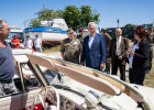 Innenminister Joachim Herrmann, Mann in Bundeswehrkleidung und weitere Personen in Konversation, im Vordergrund Oldtimer, im Hintergrund Schiffe
