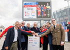 Gruppenfoto vor Kampagnenplakat mit Herrmann und Vertretern der Hilfsorganisationen um einen Notrufknopf herum.