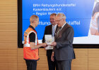 Herrmann bei der Übergabe des Ehrenamtspreises an einen Mann in Rettungsweste von der Hundestaffel