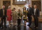 Gruppenfoto mit Blumensträußen in festlichem Raum, im Hintergrund Musiker mit Kontrabass