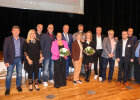 Gruppenbild der Teilnehmerinnen und Teilnehmer mit Blumensträußen auf Bühne