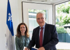 Elisa Valentin, Generaldelegierte der Regierung von Québec und Innenminister Joachim Herrmann hinter Stehtisch, Herrmann trägt sich ins Gästebuch ein