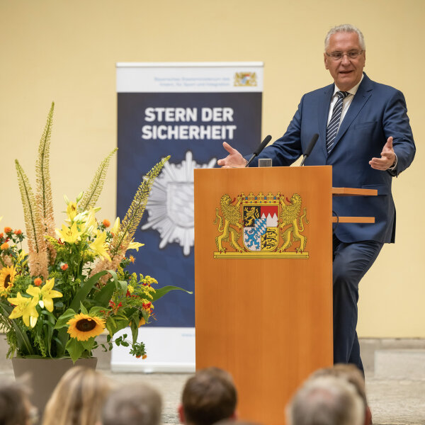 Innenminister Joachim Herrmann hinter Rednerpult, im Vordergrund Publikum von hinten