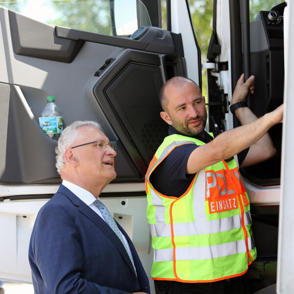 Herrmann lässt sich am Lkw von Polizist etwas zeigen