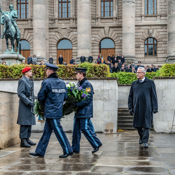 zwei Polizisten bei Kranzniederlegung, Innenminister Joachim Herrmann geht hinterher