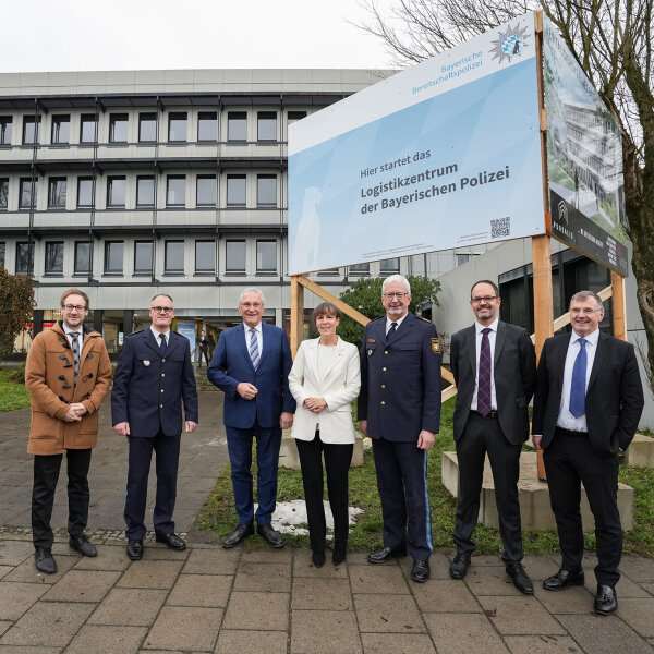 Gruppenbild vor einem Bauaufsteller mit Hinweis zum Logistikzentrum