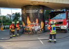 Feuerwehrleute sprühen Werbegraffiti auf einen Brückenpfeiler