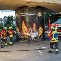 Feuerwehrleute sprühen Werbegraffiti auf einen Brückenpfeiler