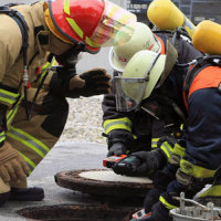 Drei Feuerwehrmänner schauen Richtung Boden Drei Feuerwehrmänner schauen Richtung Boden