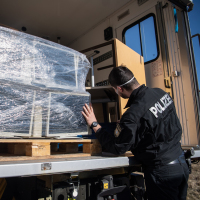 Polizist von hinten vor beladenem LKW